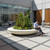 Rosetta Round Planter with Bench outside commercial building with a man sitting on it looking at his laptop