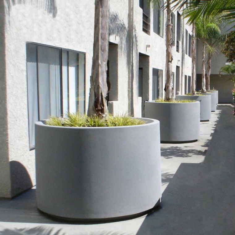 Large round Marek Planters  lined up by a condominium complex