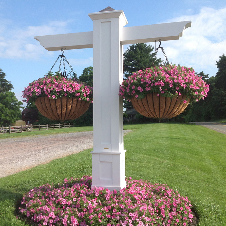 Two mega baskets hanging on a white column with flowers.