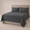 Dark Gray coverlet and pillow shams on an upholstered bed.