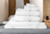 Stacked white Martex Simplicity towels in an 86% cotton and 14% polyester blend, featuring soft ribbed texture for durable hotel-quality luxury.