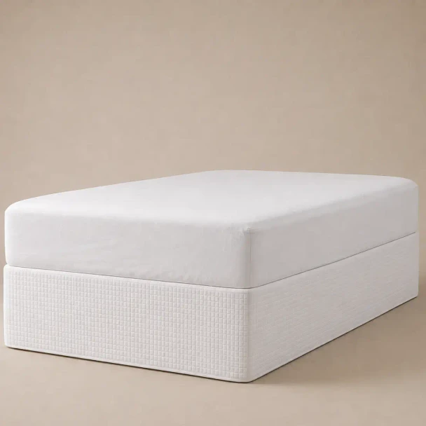 A white quilted bed skirt on a box spring under a mattress.