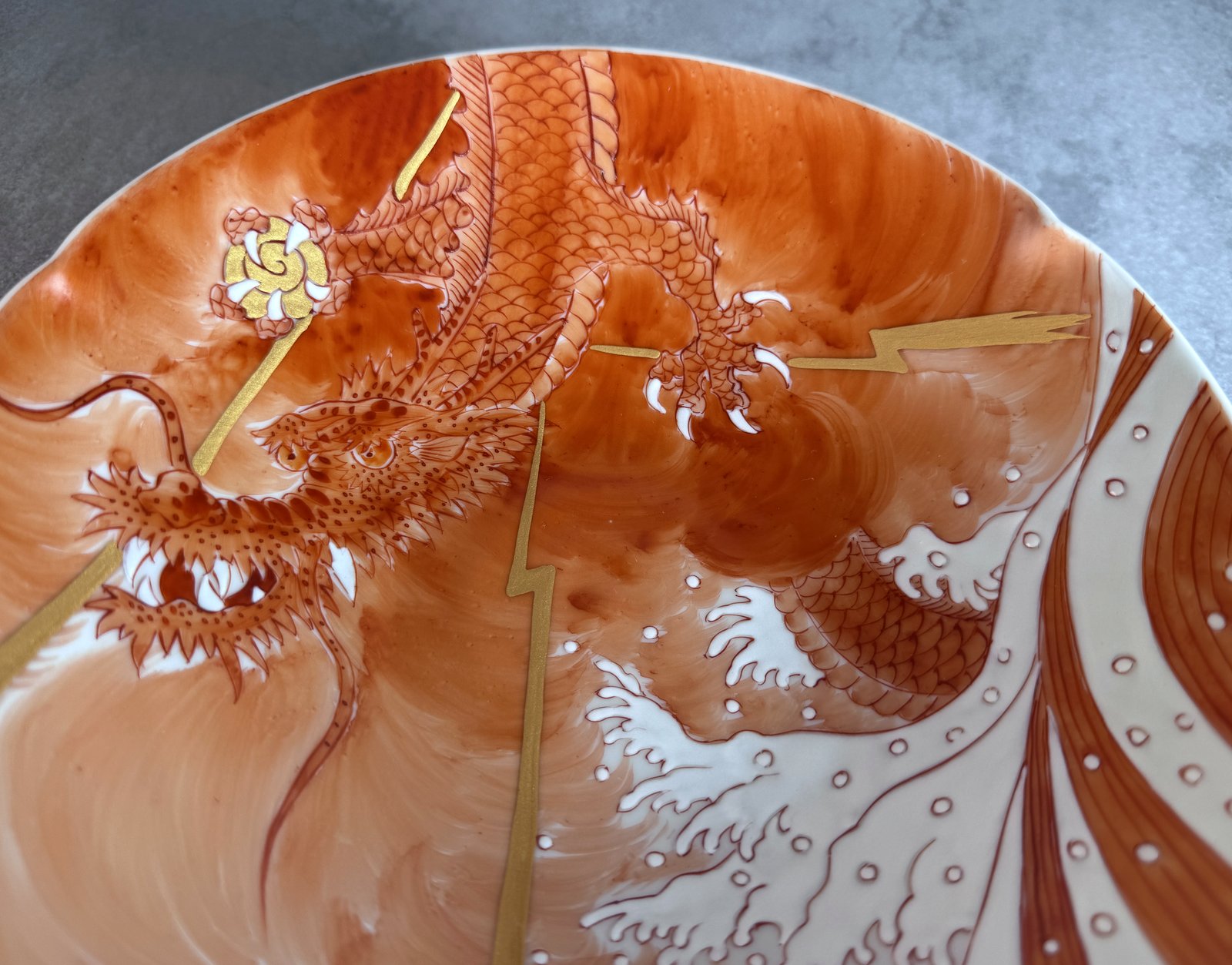 Close-up of hand-painted akae overglaze on a Kutani-yaki dragon plate