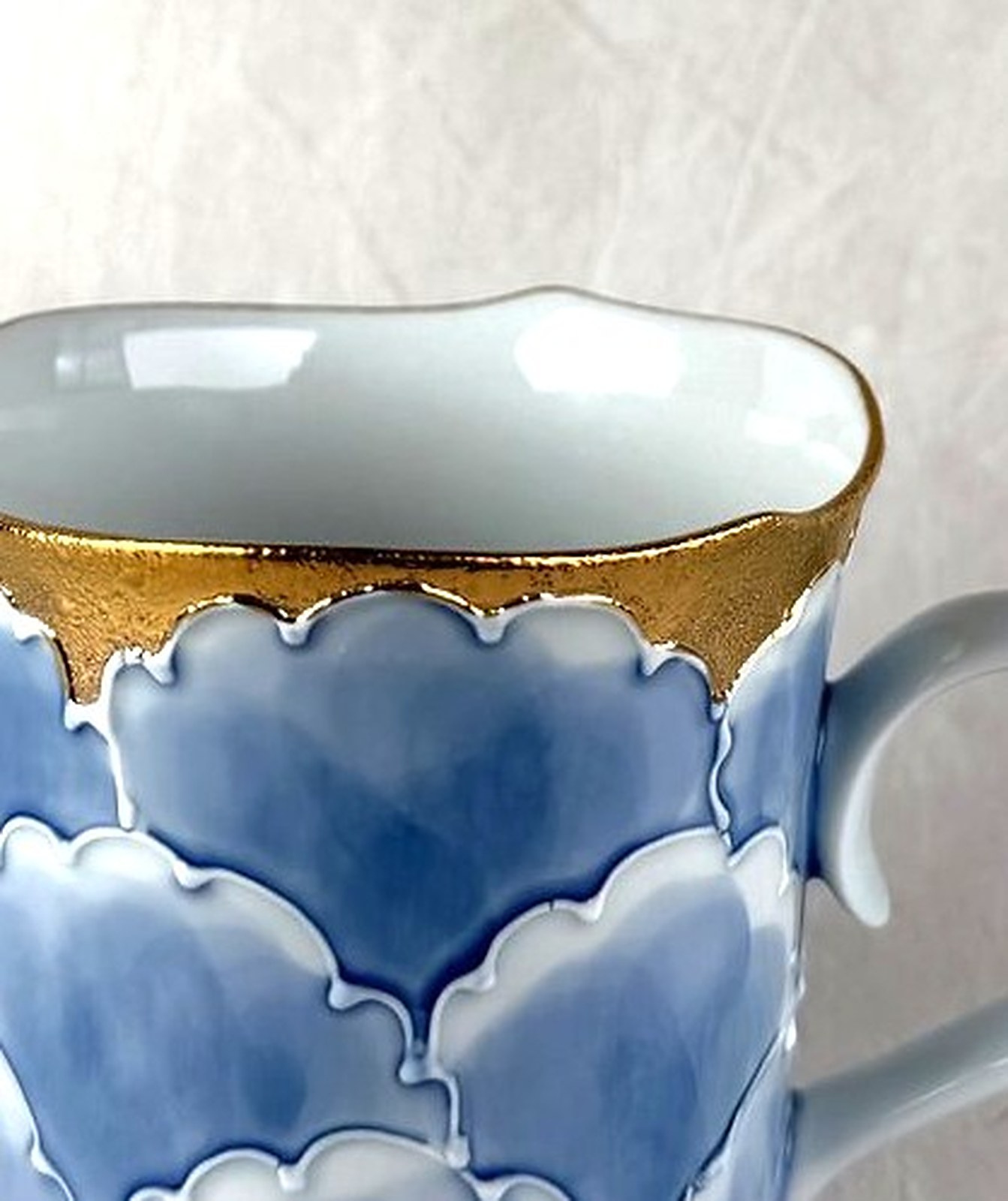 A contemporary Arita-yaki mug with soft blue cloud pattern and gold rim