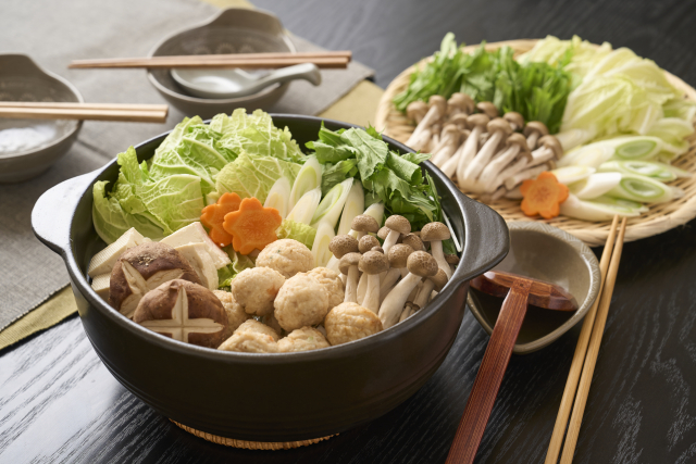 A dark pot filled with vegetables, mushrooms and round dumplings.