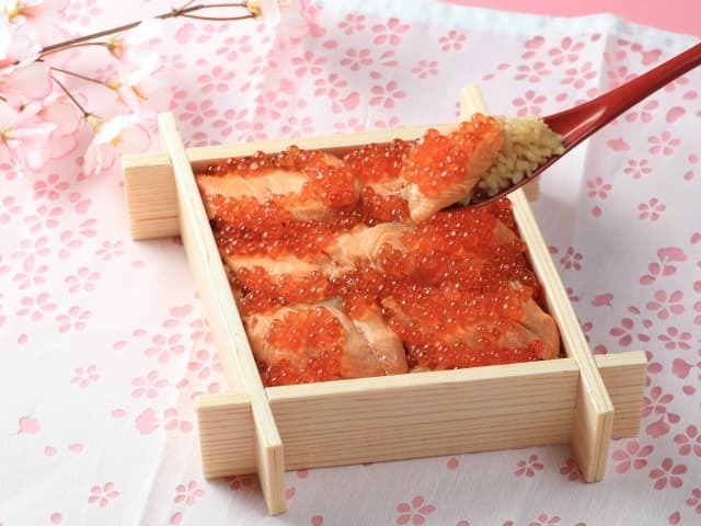 Japanese lacquered bento box with seasonal food on a cherry blossom patterned cloth