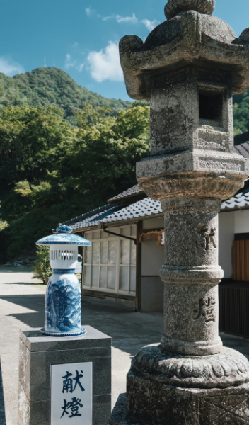 A blue and white Arita porcelain lantern beside a stone lantern at a shrine in Arita, Saga