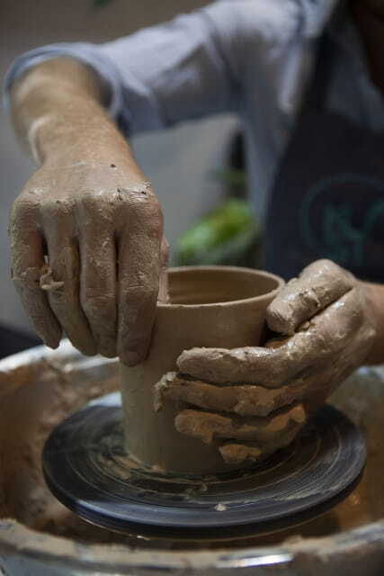 Potter's hands shaping clay on a wheel