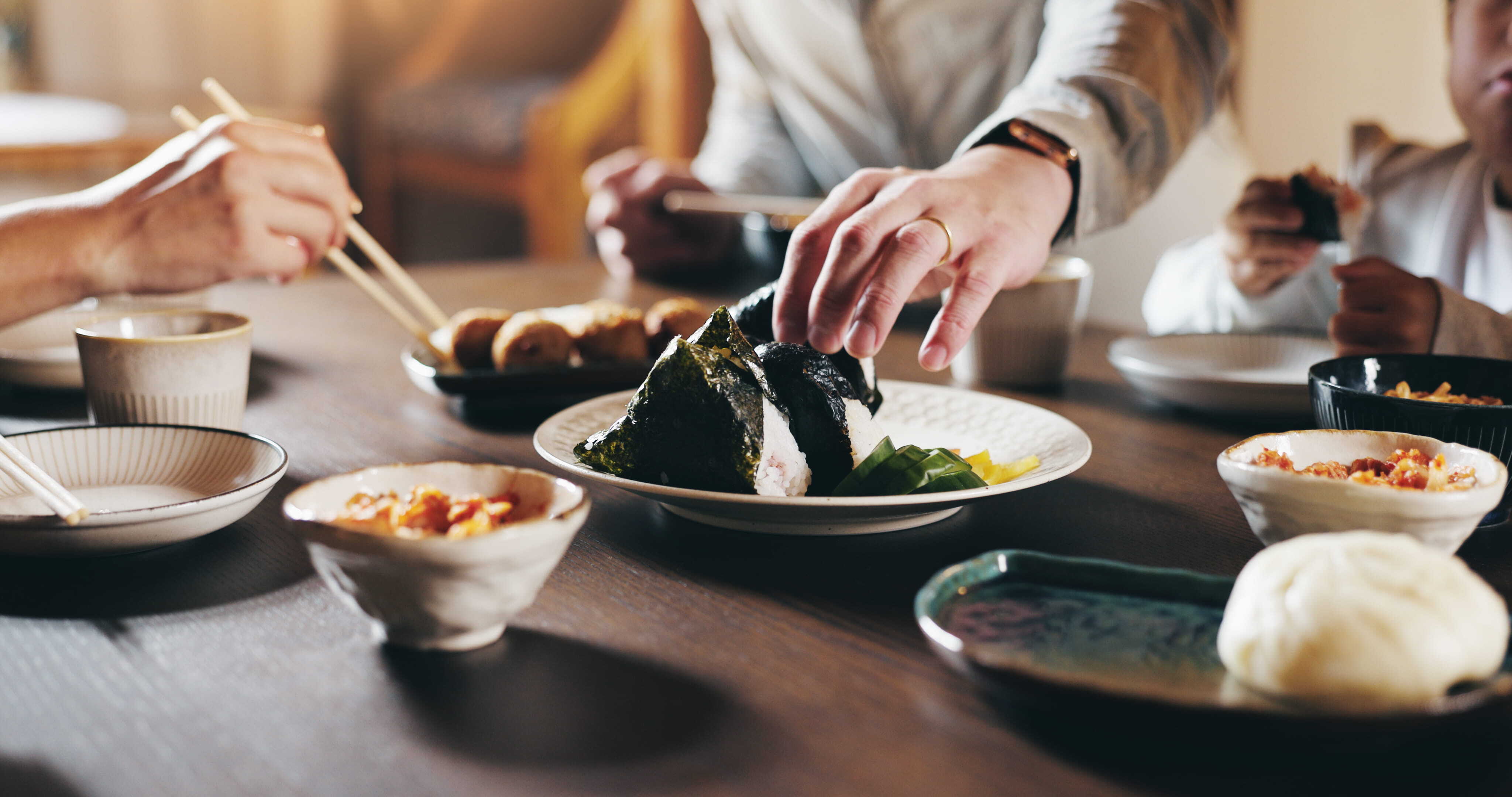 A Japanese family meal with ceramic bowls and plates on a wooden table
