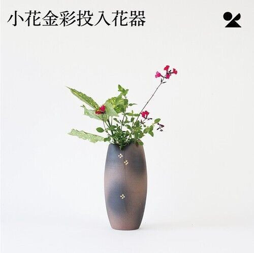 A tall, slender Shigaraki-ware vase in deep bronze-brown clay with small gold flower accents, styled on a wooden table
