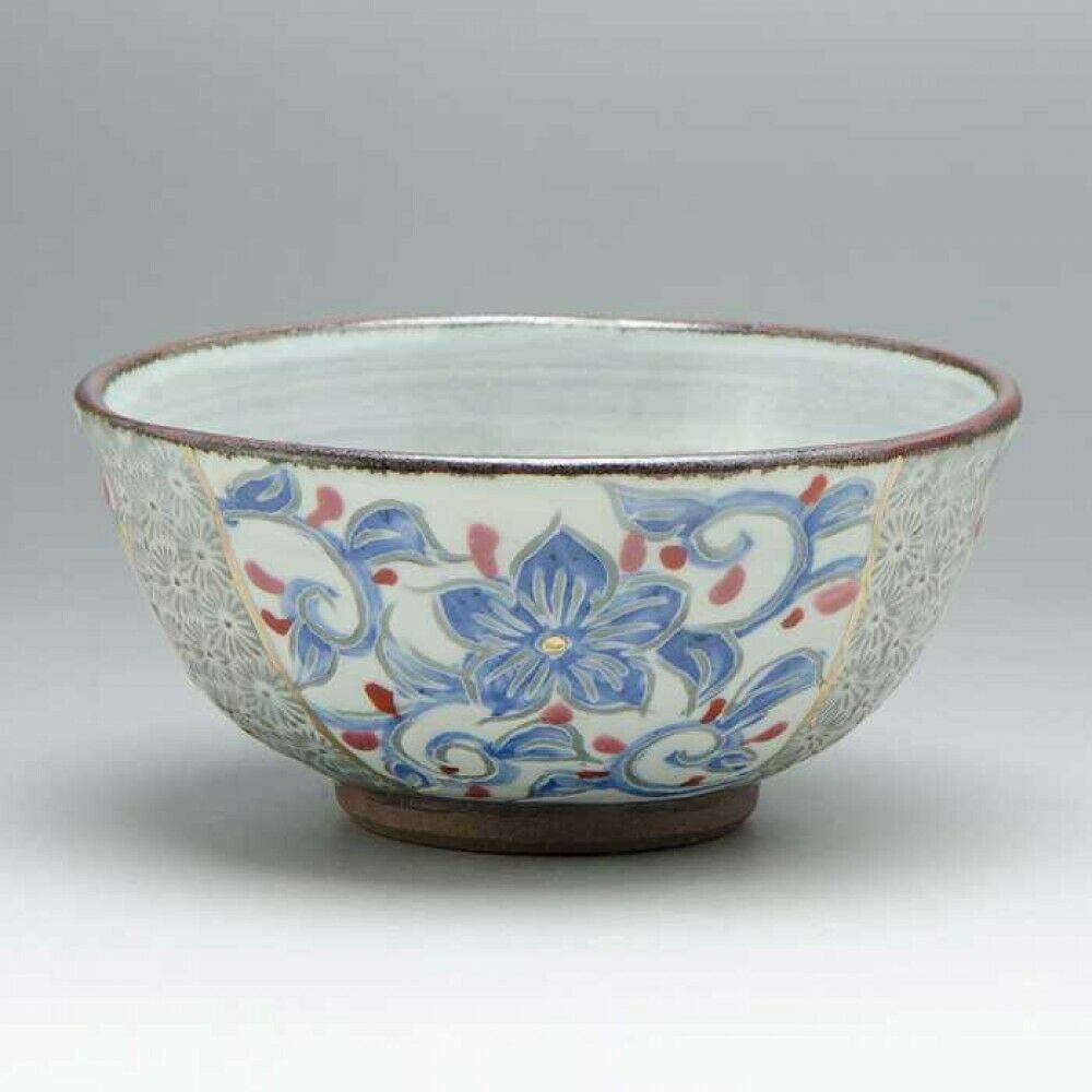 A Kyo Kiyomizu ware rice bowl with a line-carved blue and red arabesque, stamped crest panels on either side, and an unglazed clay foot