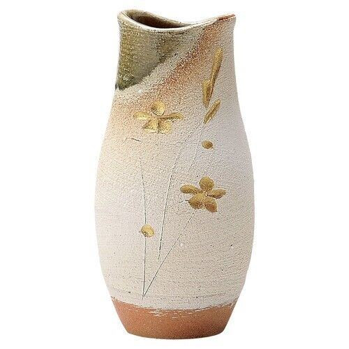 A tall Shigaraki-ware vase in cream-toned clay, with a natural ash glaze pooling toward green at the shoulder and small gilded flower accents