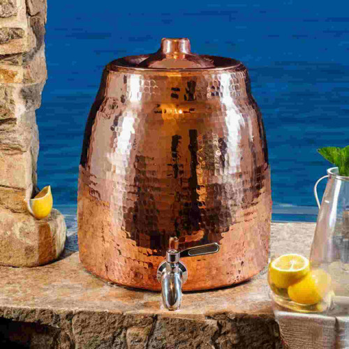 Image shows our elegant Sertodo Niagara Ayurvedic Copper Water Dispenser with Lid, on a stone ledge with.an ocean view. Your perfect hydration.