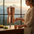 Woman enjoys our Sertodo Sana Vida Ayurvedic Copper Gravity Water Filter as a hydration centerpiece in a mountain inspired kitchen.