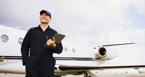 aircraft technician standing in front of a private jet while carrying a clipboard