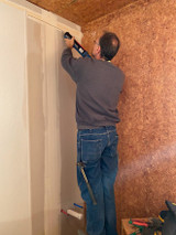 Putting adhesive on the wall to put up FRP paneling.