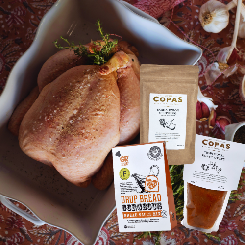 Raw chicken shown with an overlay of a packet of stuffing, a packet of bread sauce and a packet of gravy