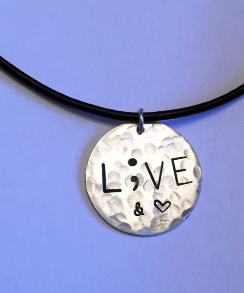 Semicolon LIVE & Love (Heart Shape) Sterling Silver Round Stamped Recovery or Prevention Necklace and choice of chain. It is shown Hammered on a Black Leather Chain. Choose from five custom finish options. Use the drop down menu to add Genuine Swarovski Birthstones.

This piece is inspired by the Project Semicolon Movement. Project Semicolon (The Semicolon Project) is a faith-based non-profit movement dedicated to presenting hope and love to those who are struggling with depression, suicide, addiction and self-injury. "A semicolon represents a sentence the author could have ended, but chose not to. The sentence is your life and the author is you." - Project Semicolon

SIZE: 
Solid Sterling Silver 7/8" Round