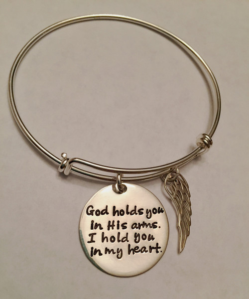 Hand Stamped Round "God holds you in His arms, I hold you in my heart." Expandable Bangle Bracelet & Angel Wing Charm, all .925 Sterling Silver. Memorial Bracelet, one size fits most. It is shown with a Polished Finish on a Solid Sterling Silver Bangle. Choose from five custom finish options. Use the drop down to add Genuine Swarovski Birthstones. 

SIZE: 
Expandable one size fits all 2 1/2"-3" Solid Sterling Silver Bangle Bracelet 1.5mm.
One Solid Sterling Silver 1" Round stamped, "God holds you in His arms, I hold you in my heart."
One Solid Sterling Silver Angel Wing Charm.