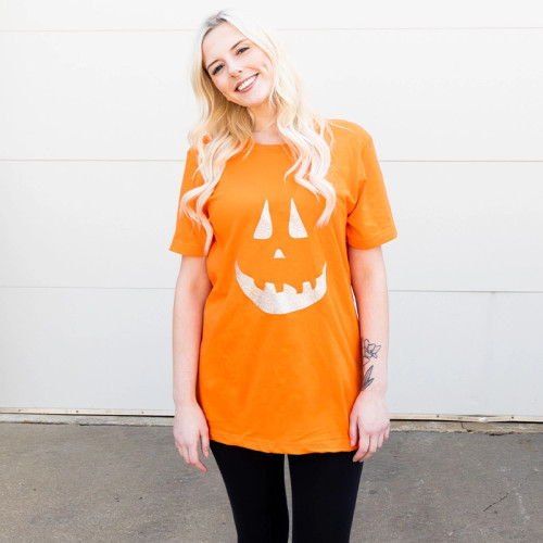 A festive Halloween t-shirt costume featuring a large, grinning pumpkin face. The orange shirt serves as the pumpkin's body, while the pumpkin's eyes, nose, and toothy smile glowing. It's an easy and cheerful Halloween costume option for your night out in Fargo, ND!