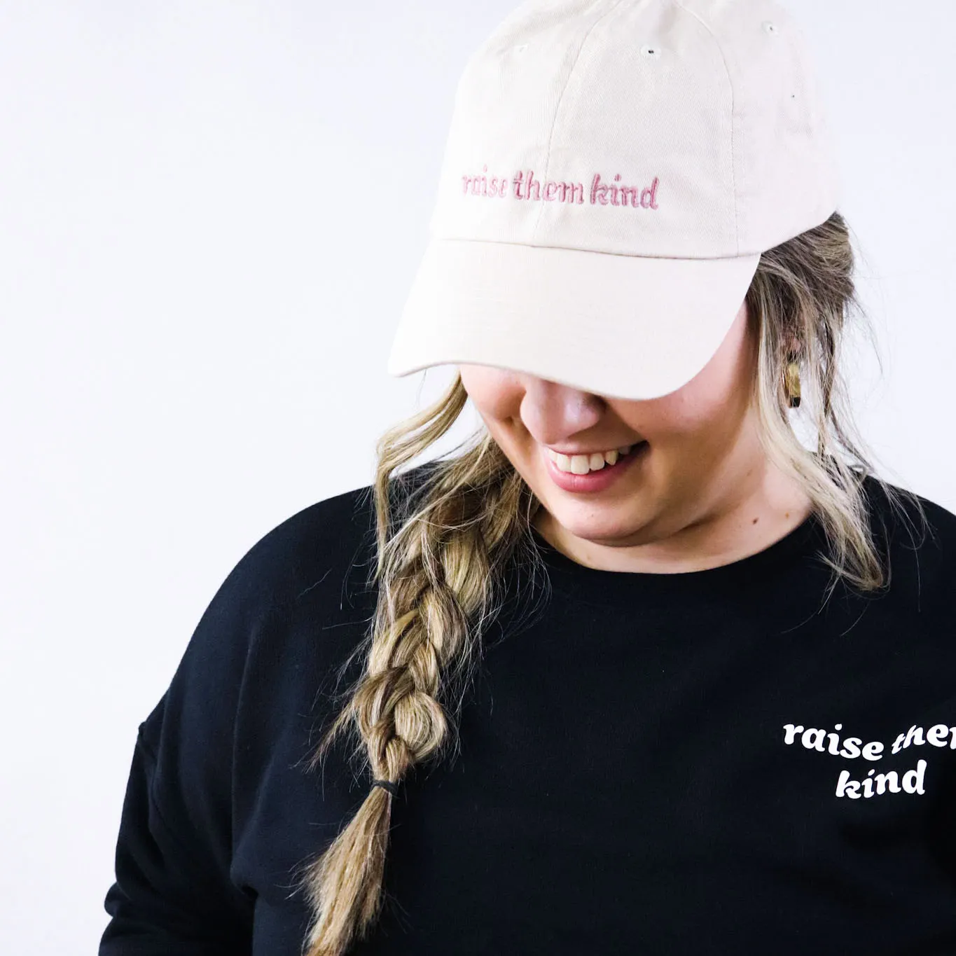 Woman wearing a baseball hat and crewneck