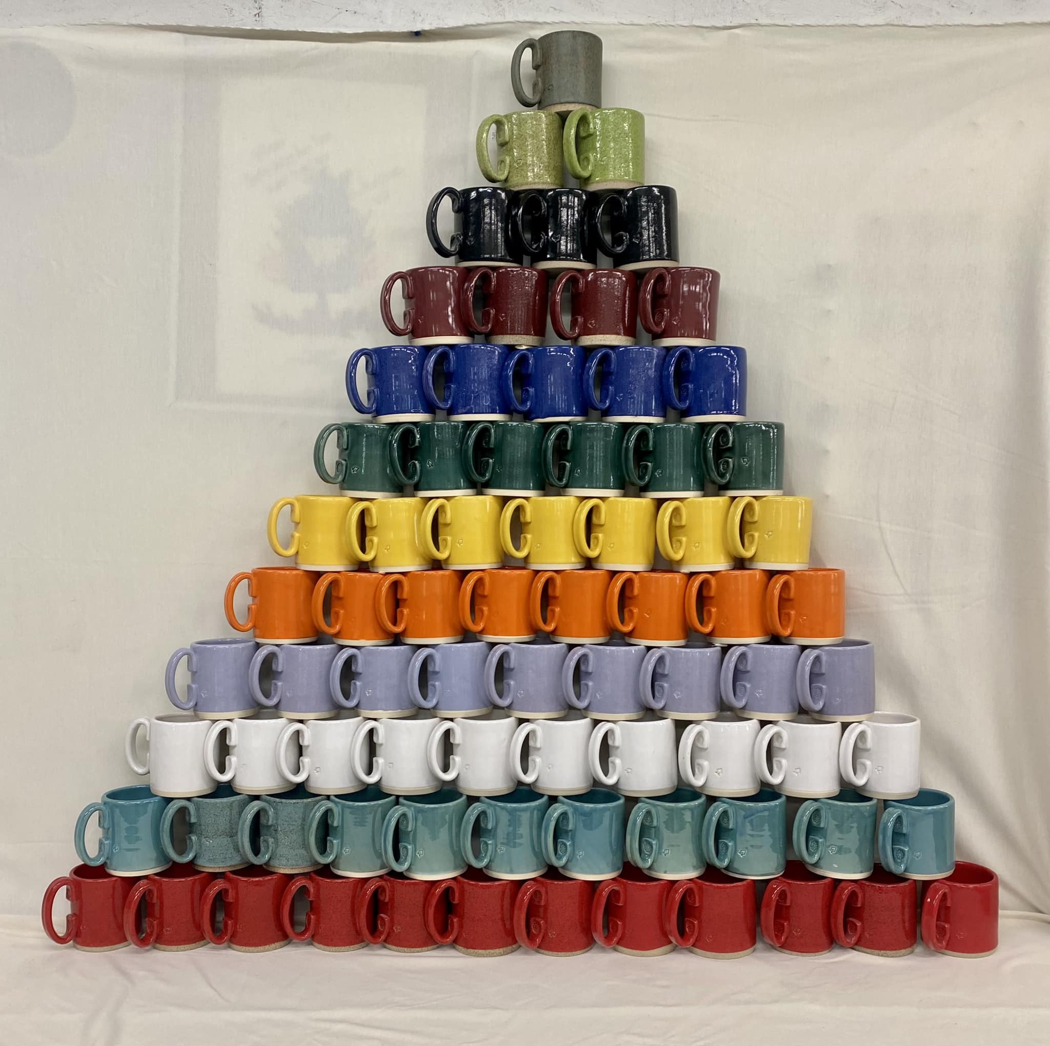 A stack of mugs in rainbow colors