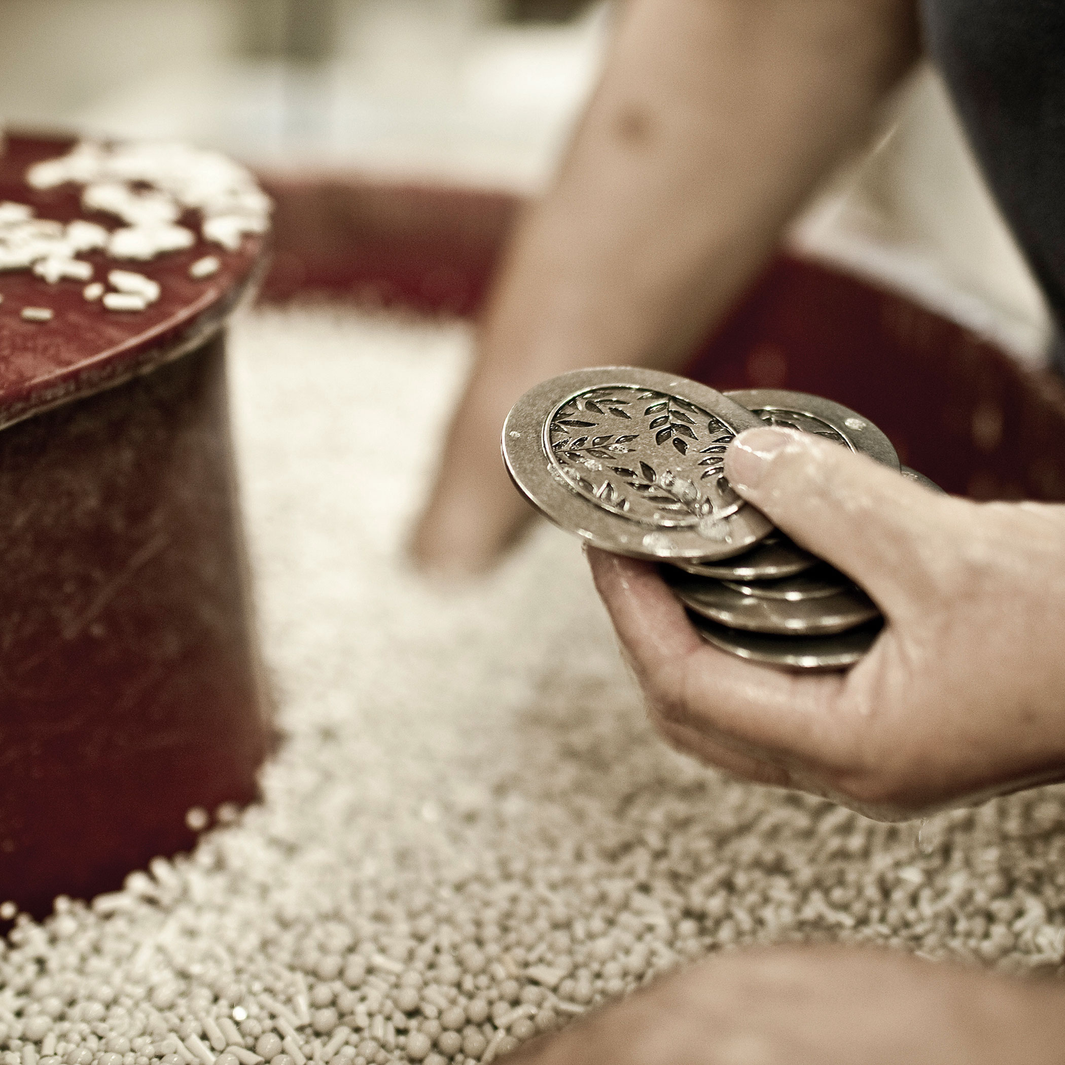 Hand pulling pewter pieces out of a tumbling vat