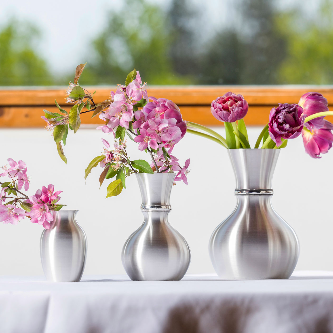 Pewter vases in multiple sizes and shapes with pink flowers