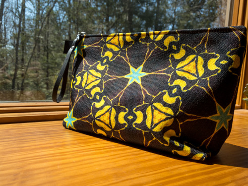 Large marigold cogs essential accessory clutch with zipper pull basking in the sun.