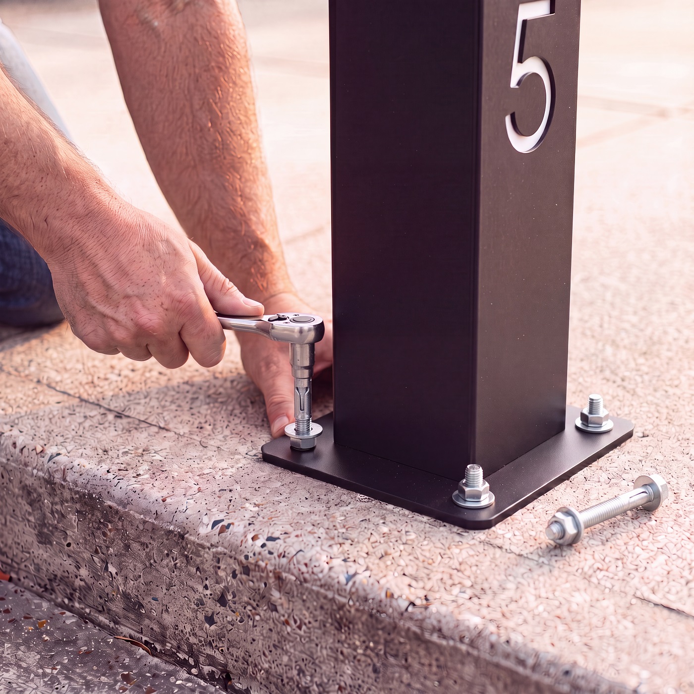 Base plate anchored to concrete with a socket wrench