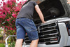 Iron & Haft Men's Journeyman Work Jean Shorts IHJSH, a person working on a car engine wearing denim shorts in front of pink flowering trees.
