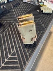LAPG PMAG Magazine Coupler, tan magazine coupler holding multiple rifle magazines on a workbench. Thumbnail Image