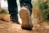 OTB Boots Incline Mid Waterproof Tactical Boot, close-up view of a person's foot walking on dirt trail, showing the rugged sole designed for outdoor and tactical activities. Thumbnail Image