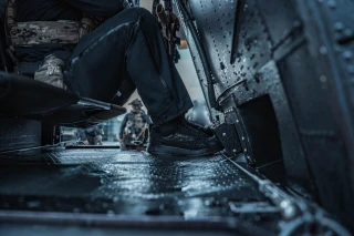 OTB Boots T-KOOL Mid Low-Viz Tactical Boot, close-up of black tactical boot on a wet aircraft floor.