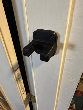 LAPG AR-15 Buffer Tube Wall Mount, black firearm wall mount for AR-15 buffer tubes on a white door.