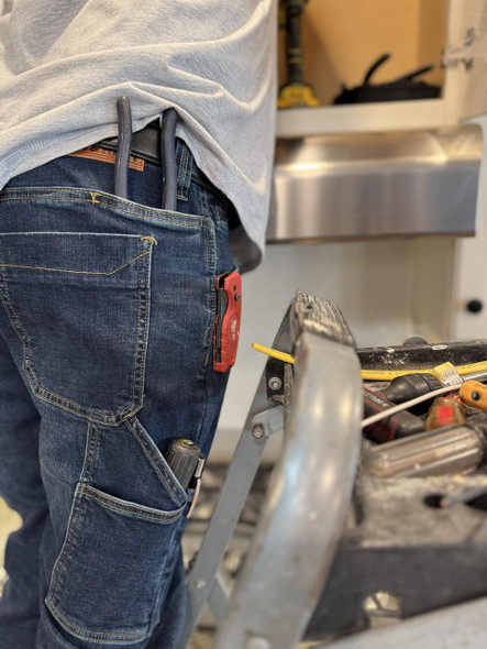 Iron & Haft Men's Journeyman 12 Pocket Stretch Work Jean, close-up of the back pocket with tools and a multi-tool clipped to the pocket on a worker wearing denim jeans.