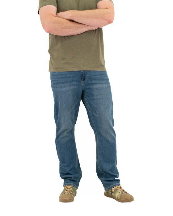 LAPG Men's Core Flex 6 Pocket Stretch Jean, full-length image of a man wearing blue jeans, a green T-shirt, and tan sneakers, with arms crossed.