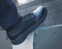 OTB Boots Fusion 8 Black Tactical Boot, a close-up of a black tactical boot worn by a person, showcasing its durable design and rugged sole.