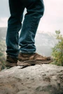 OTB Boots Incline Mid Waterproof Tactical Boot, close-up of a person standing on a rock outdoors wearing brown tactical boots with rugged soles and waterproof design.