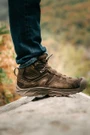 OTB Boots Incline Mid Waterproof Tactical Boot, close-up of a person wearing brown waterproof tactical hiking boots on a rock with an outdoor background.