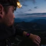 Suunto Core 2 Classic Outdoor Watch, a rugged wristwatch with a black rubber strap and digital display, worn by a person hiking during dusk with a mountainous landscape in the background.