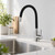 Grifo de cocina con caño flexible negro mate y cuerpo de acero satinado, instalado junto a un fregadero de acero