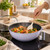 Wok de 24 cm salteando verduras y gambas sobre placa de inducción con la espátula del set