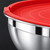 Borde enrollado de un bol de acero inoxidable plateado con franja pulida y tapa roja de anillos en relieve con lengüeta