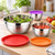 Tres boles de acero inoxidable plateado con ensalada y tomate en una encimera, con tapas roja, naranja y morada
