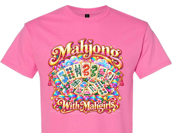 The image shows a pink t-shirt with a colorful graphic printed on it. The graphic is centered on the chest area of the t-shirt and features the text "Mahjong" in large, stylized, golden lettering at the top. Below this, the text "With Mahgirls" is written in similar golden lettering.

The design is elaborate and whimsical, incorporating many elements related to the game of Mahjong and a festive, playful aesthetic. Several Mahjong tiles are arranged in a fan shape, with some tiles facing forward and others angled. These tiles depict various symbols commonly found in Mahjong, such as bamboo stalks, characters, red dragons, green dragons, and floral motifs like peonies and cranes.

Surrounding the Mahjong tiles and text are numerous decorative elements. There are stylized clouds in pastel blues and purples, sparkling stars in yellow and gold, and an abundance of pink flowers, possibly cherry blossoms or lotus flowers. Intertwined with these are colorful rainbow ribbons and bows, as well as heart shapes in various shades of pink, purple, and blue. The overall color palette is vibrant and cheerful, dominated by pink, gold, blue, green, red, and rainbow hues.

The composition is radial, emanating from the center where the Mahjong tiles are displayed. The text elements are prominent and framed by the decorative motifs, creating a cohesive and eye-catching design. The overall style is illustrative and somewhat retro, with a glossy, almost three-dimensional appearance to the lettering and some of the decorative elements. There are also subtle watermark-like text overlays on the t-shirt, indicating copyright information. The t-shirt itself is a plain pink crew-neck with short sleeves.