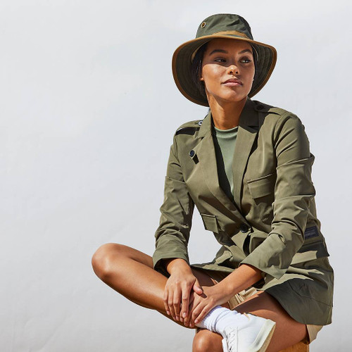 Person wearing the Tilley TWC7 Green Outback Waxed Cotton Hat sitting cross legged wearing a green blazer against a white backdrop