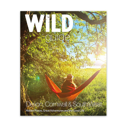 Wild Guide Devon, Cornwall & South West travel guide front cover with an image of a person sat in a hammock looking over a rural landscape