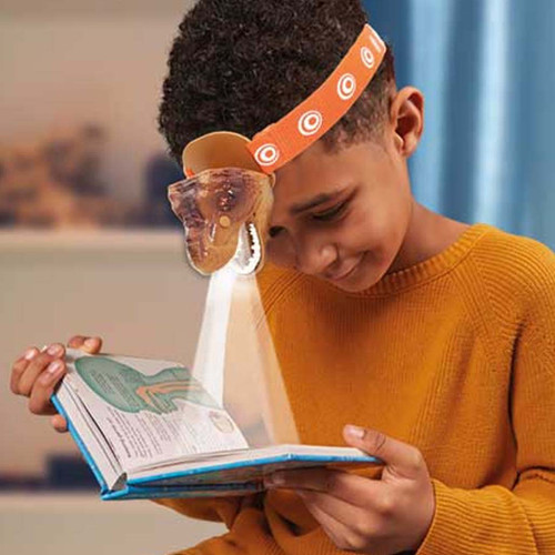 Child wearing T-Rex Kids Headlamp from Brainstorm and reading a book using the head torches light