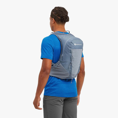 Person wearing Montane Trailblazer 18 Backpack in Stone Blue an angled front view showing the front pockets, straps and printed logo